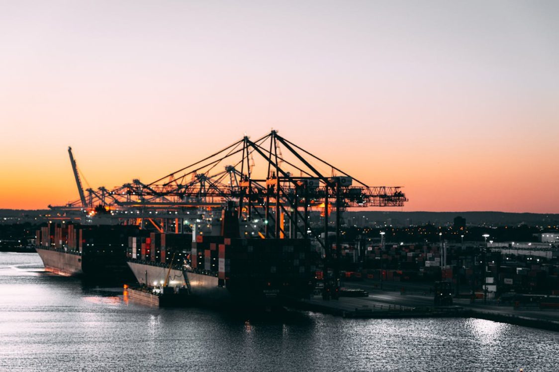 Container ship loading at port at sunset — trusted logistics since 1938